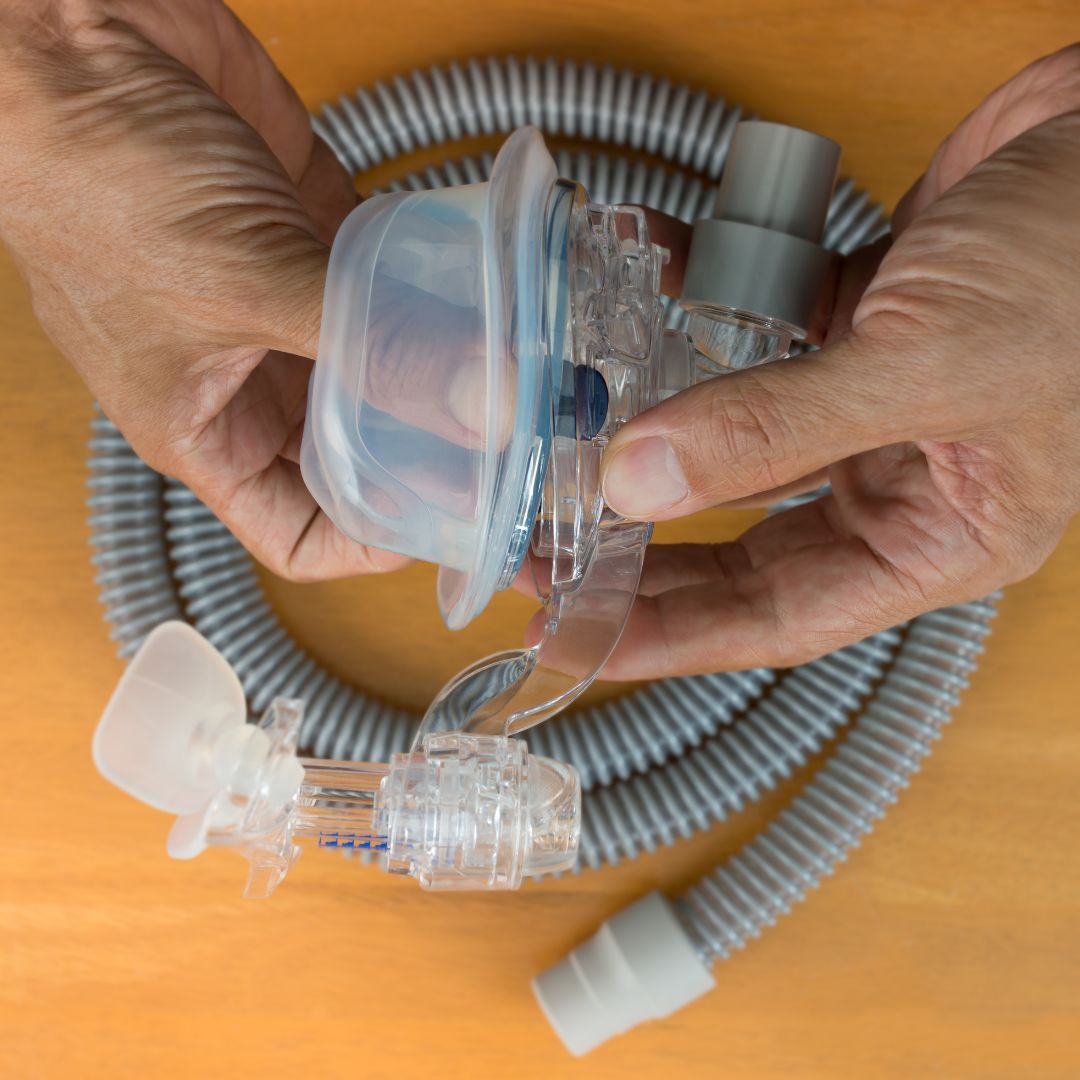 Hands taking apart a CPAP machine mask