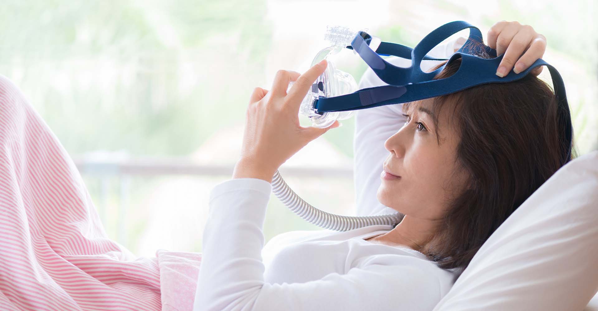 woman laying down and putting on cpap