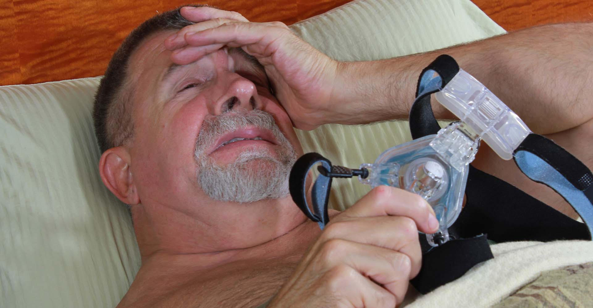 man showing distress while holding his cpap