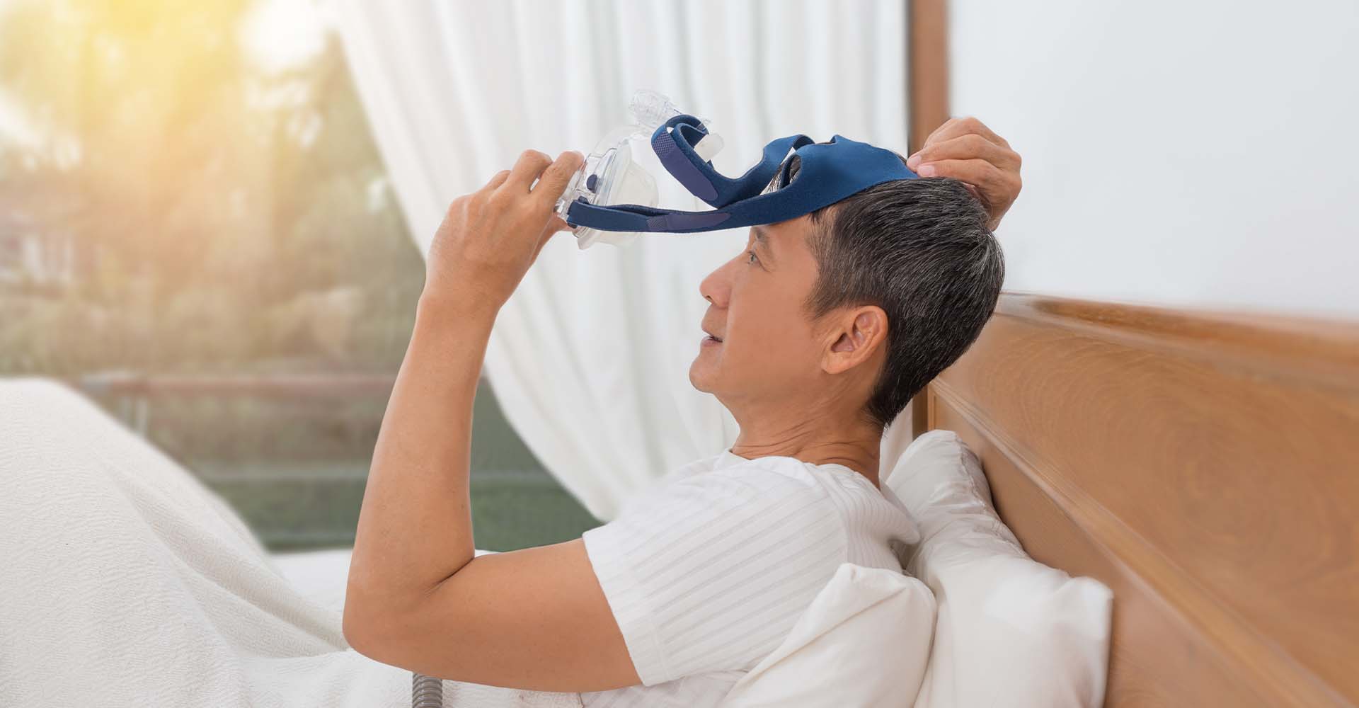 A man removing his cpap mask in bed