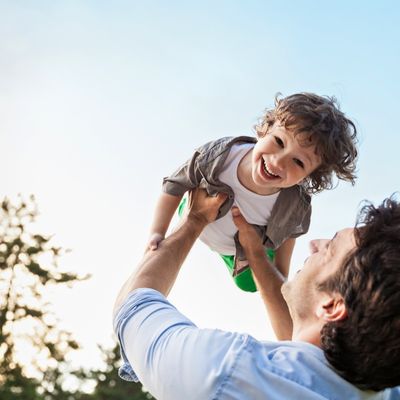 A father picking up his son while outside having fun