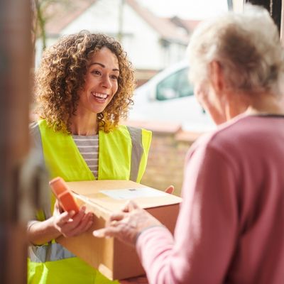 A happy woman delivering a package to an elderly woman