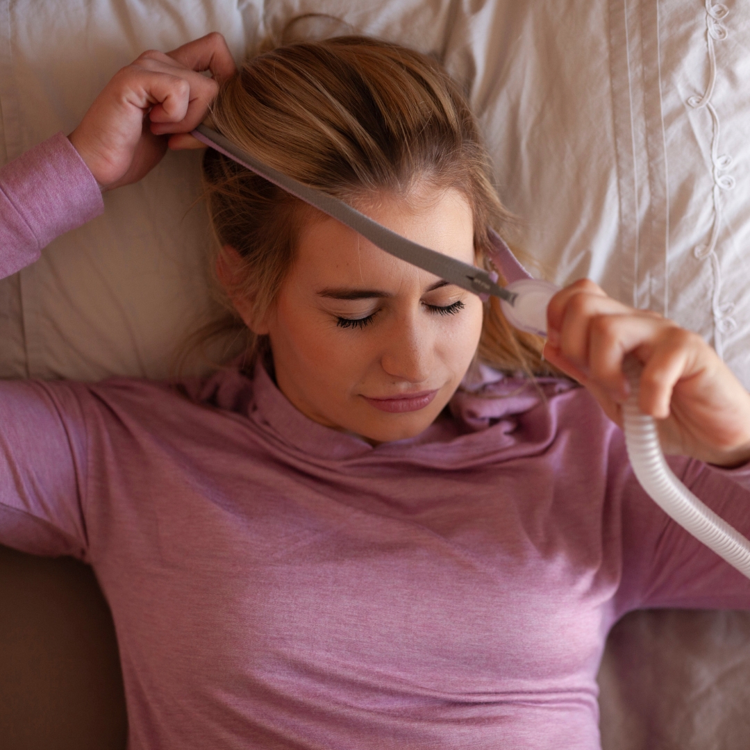 Woman putting on the mask of a CPAP machine